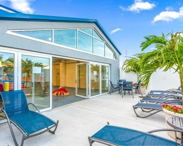 View of sun deck with blue skies, blue lounge chairs, and palm trees